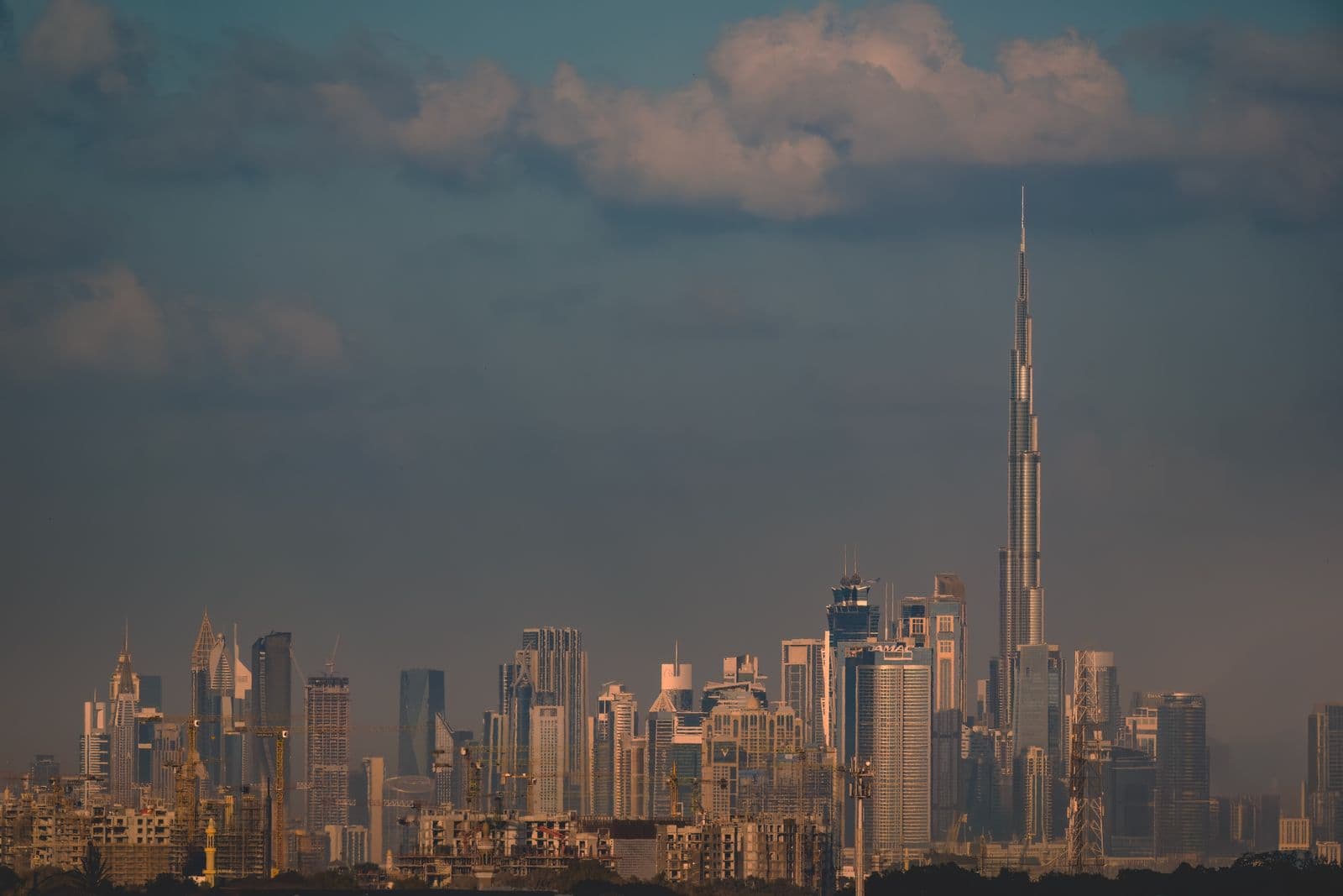 The Dubai skyline at dusk with the Burj Khalifa lit against a blue sky