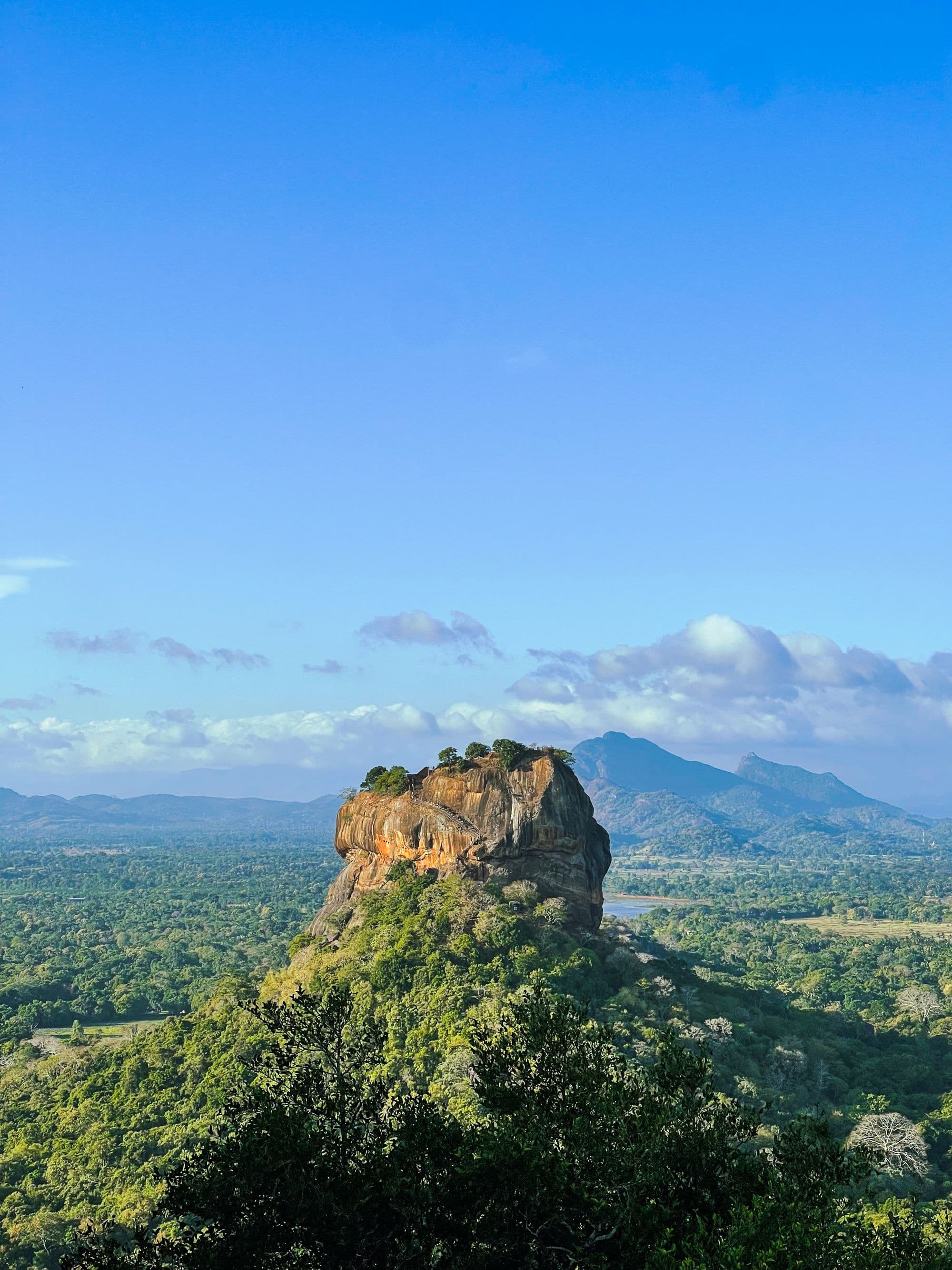 Sigiriya rock fortress rising above forest and water at first light
