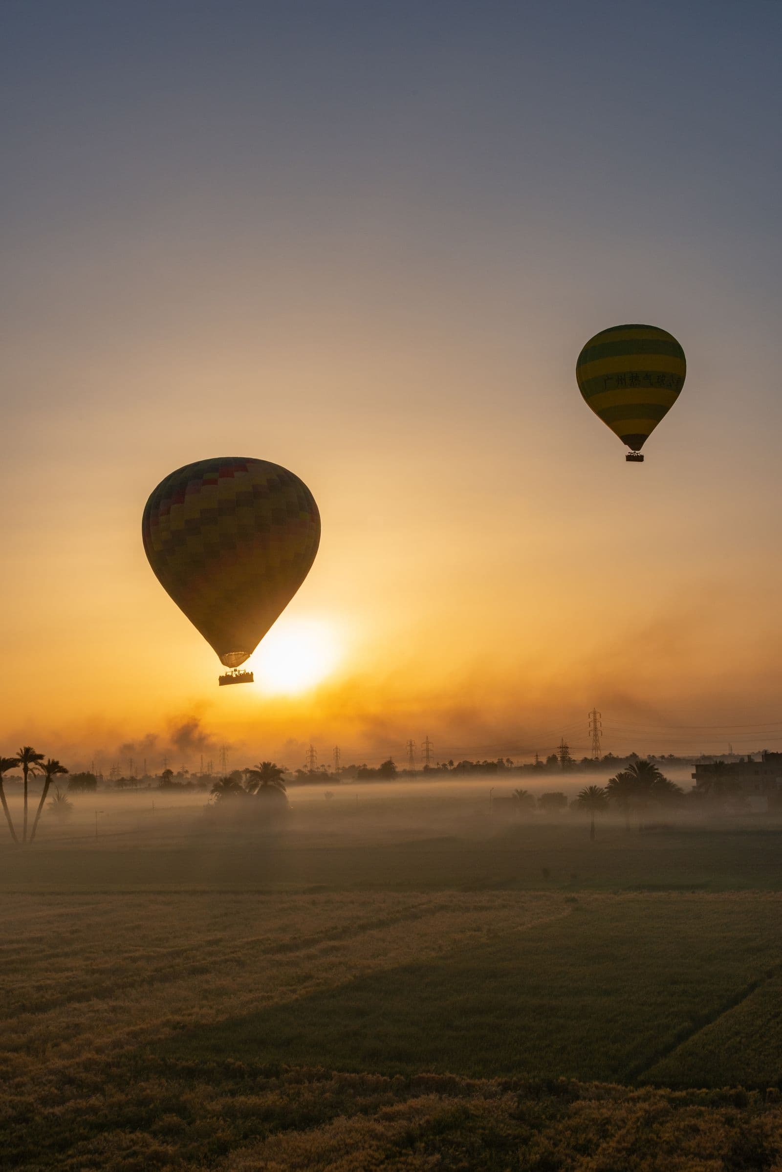A hot air balloon drifting over paddy fields near Sigiriya at sunrise